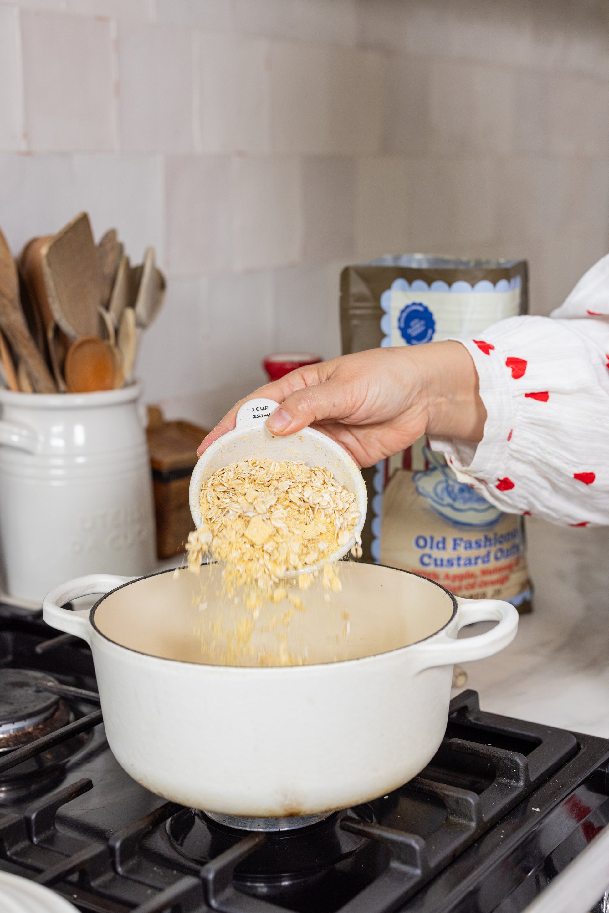 Person adding oats to a pot on a stove