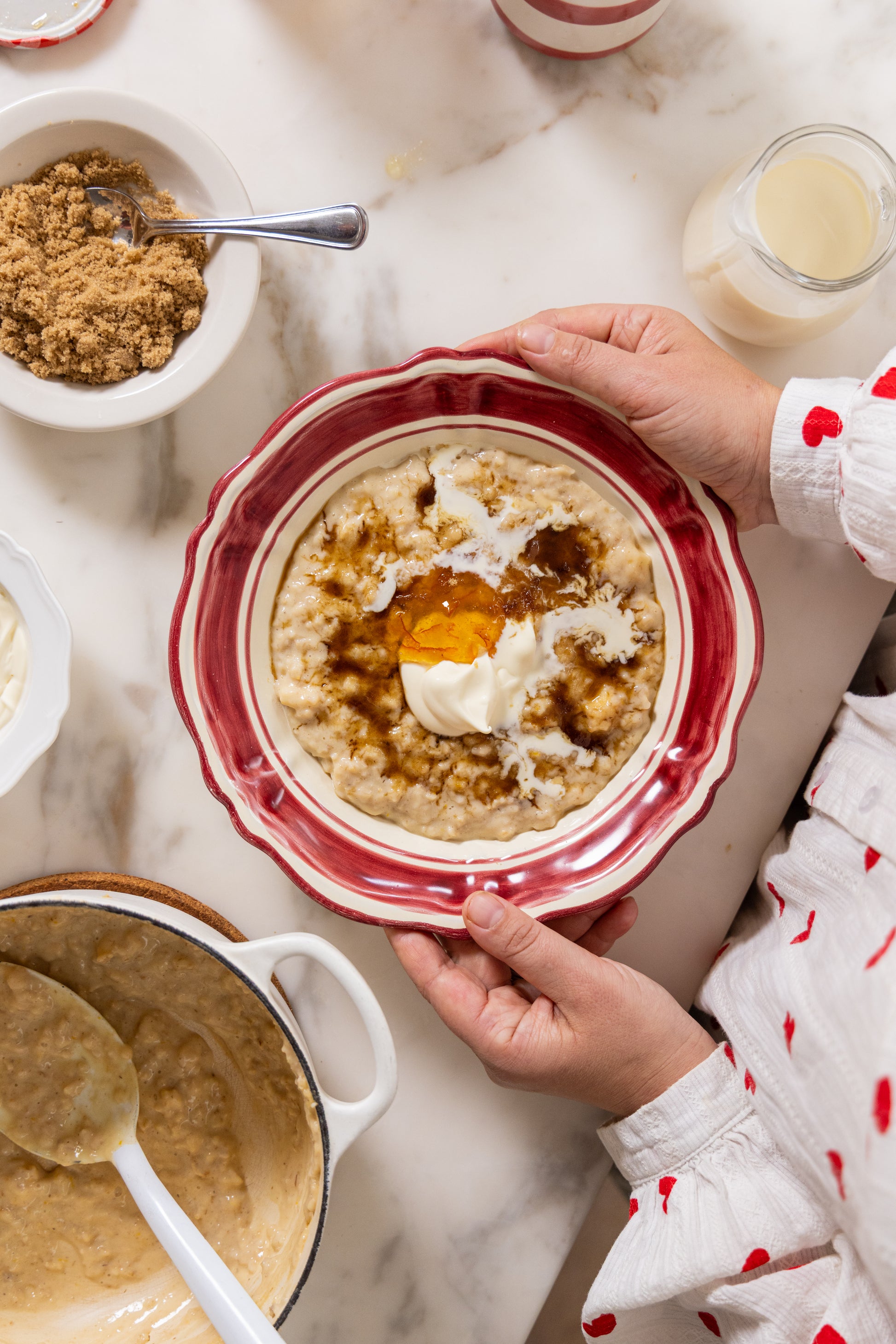 Person holding a bowl of oats with toppings on a marble surface