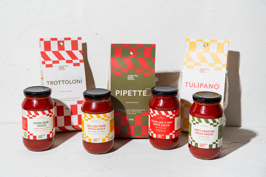 Four jars of pasta sauce and 3 packets of pasta with their packaging on a white background